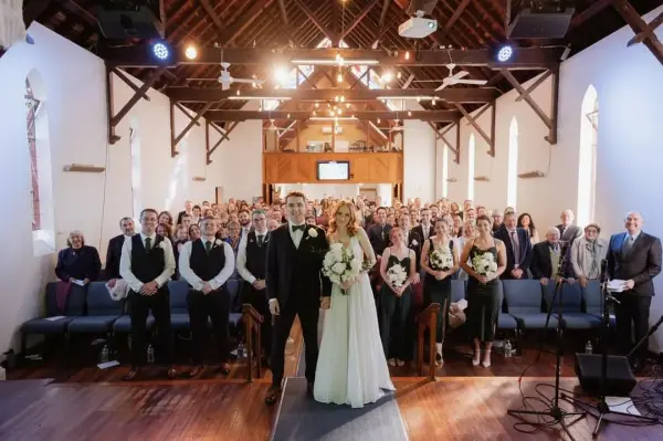 A bride and groom with their bridal party and wedding guests standing inside the church