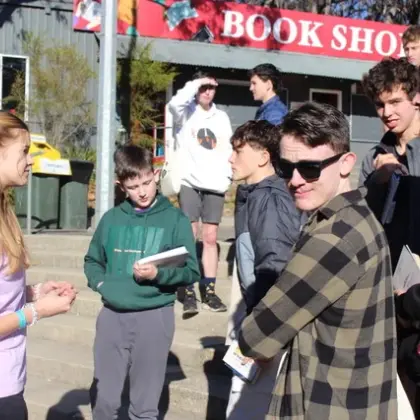 A youth leader talking with a group of teenagers outside a book shop