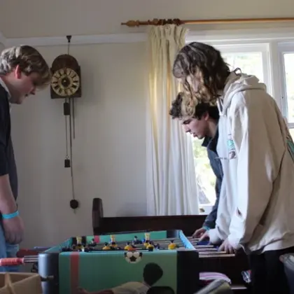 Teenagers playing table soccer in a lounge room