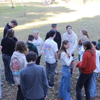 A large group of teenagers gathered in a circle on the grass