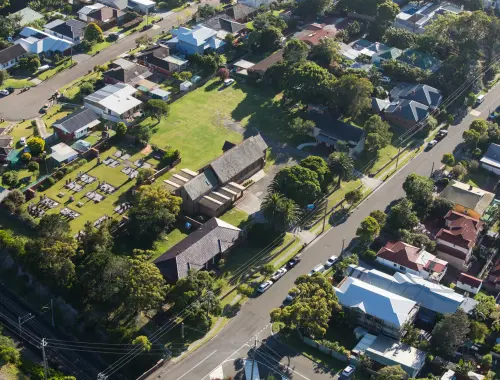 Aerial view of Bulli Anglican Church and its historic graveyard, surrounded by the streets of Bulli beside the railway line
