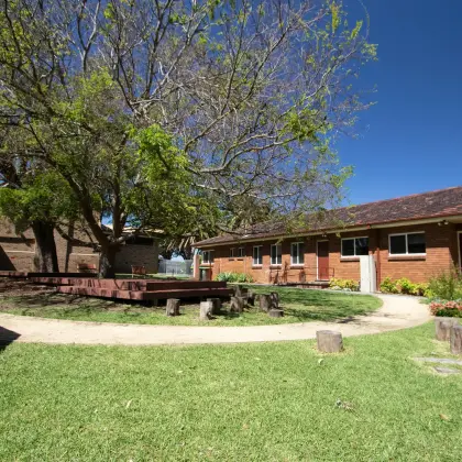 Curved path around the playground lawn, with log stepping stumps and the brick ministry centre behind