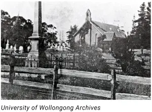 Black and white photo of St Augustine's Church, Bulli, in the 1930s, behind a timber fence with the memorial obelisk and graveyard (University of Wollongong Archives)